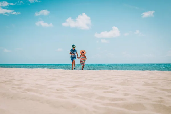 Glad pojke och flicka som springer på stranden — Stockfoto