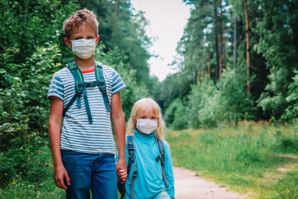 Хлопчик і дівчинка з масками і шкільна сумка ходять до школи після карантину корона — стокове фото