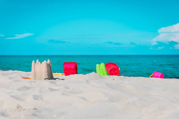 Castillo de arena en la playa con juguetes, vacaciones en familia —  Fotos de Stock