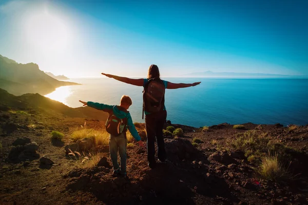 Silhueta de feliz mãe e filho viajam nas montanhas do pôr do sol — Fotografia de Stock