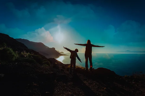 Silhueta de feliz mãe e filho viajam nas montanhas do pôr do sol — Fotografia de Stock