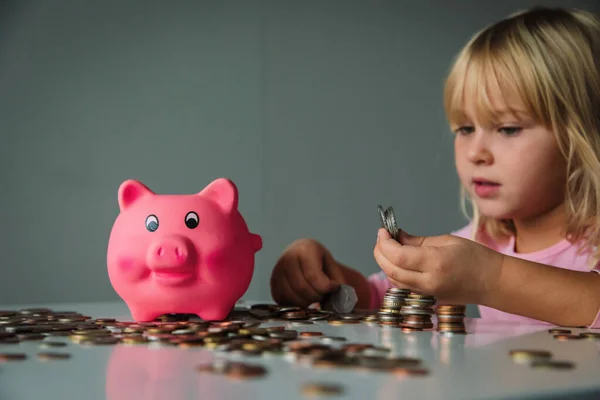 Дитина заощаджує гроші, мила дівчина кладе монети в скарбничку — стокове фото