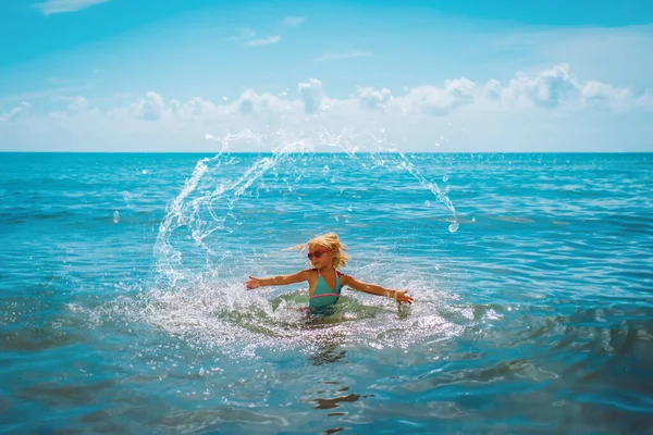 Šťastný roztomilý dívka splash voda na pláži — Stock fotografie