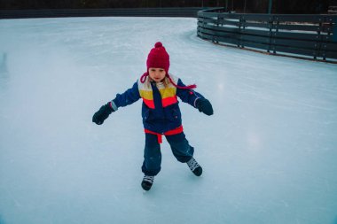 Mutlu küçük kız kışın paten kaymayı öğreniyor.