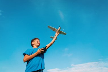 Çocuk doğada uzaktan kumandalı uçak uçuruyor.