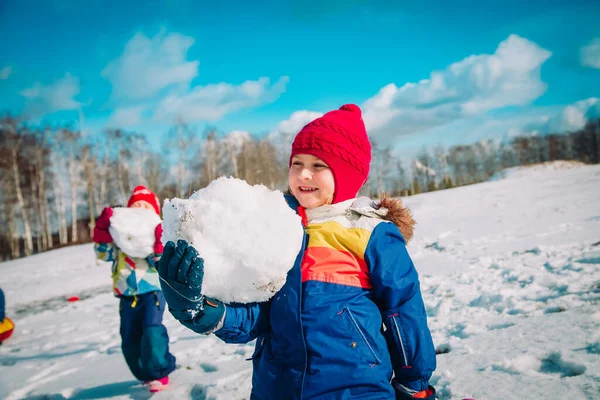 Χαρούμενα παιδιά χτίζουν χιονάνθρωπο στη χειμερινή φύση — Φωτογραφία Αρχείου