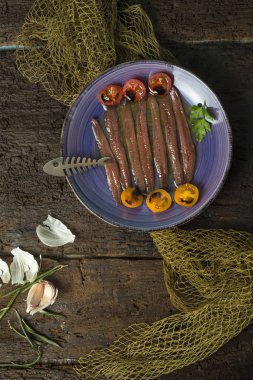 Zeytinyağı, domates ve sarımsak eski ahşap masa, Natürmort salamura hamsi tabak. Dikey görüntü.