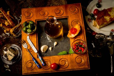 Ekstra saf zeytinyağı, ilk soğuk ütülü, eski ahşap bir mutfakta organik yiyeceklerle çevrili cam bir kavanozda.