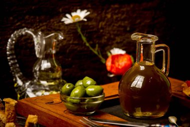 Ekstra saf zeytinyağı, ilk soğuk sıkılmış, kırsal arka planda yeşil zeytinli cam bir kavanozda..