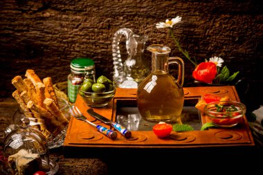 Extra quality virgin olive oil in a glass jar, surrounded by food in a rustic kitchen clipart