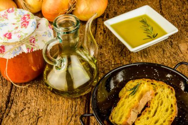 Ekstra saf zeytinyağı, kaliteli cam kavanoz, soğan ve eski ahşap masada korunmuş domates..