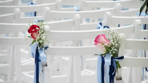 white chairs decorated with flowers and ribbons in wedding venue