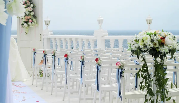 white chairs decorated with flowers and ribbons in wedding venue