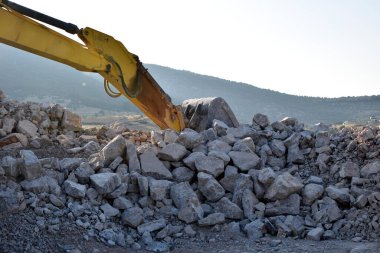 Taş blokların arasında kazıcı kovası