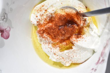 Beyaz arka planda izole edilmiş çay tabağında yoğurt kırmızı biber ve zeytinyağı ile beyaz sos. 