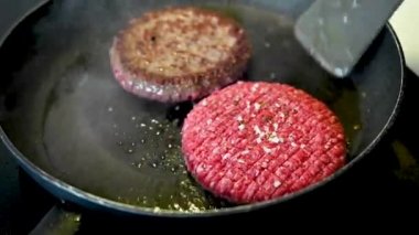 Sıcak tavada kızaran tuzlu ve otlu iki büyük kırmızı biftek. Biftekler kızgın yağda cızırdıyor. Biftekler diğer tarafa çevrildi. Brian Holm Nielsen 'in stok görüntüleri