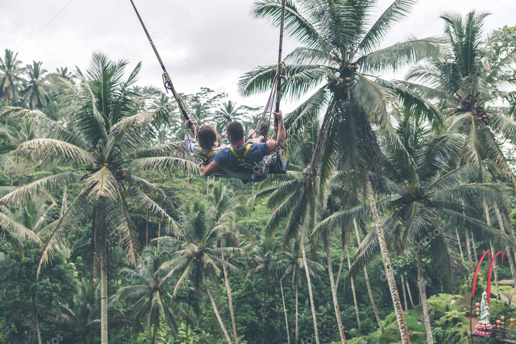 Couple swings in the deep jungle of Bali island.