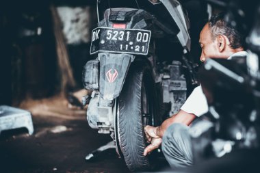 Bali, Endonezya - 17 Mayıs 2018: Motosiklet Lastik değiştirme, yükleme garajda. Scooter motosiklet tamiri.