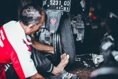 Bali, Endonezya - 17 Mayıs 2018: Motosiklet Lastik değiştirme, yükleme garajda. Scooter motosiklet tamiri.