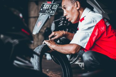 Bali, Endonezya - 17 Mayıs 2018: Motosiklet Lastik değiştirme, yükleme garajda. Scooter motosiklet tamiri.