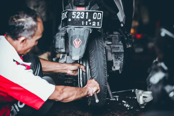 BALI, INDONESIA - 17 Mei 2018: Penggantian ban sepeda motor, pemasangan di garasi. Skuter kumbang sedang diperbaiki . — Stok Foto