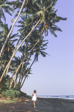 Genç kadın bir siyah kum plaj, Bali Adası.