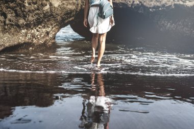 Genç kadın bir siyah kum plaj, Bali Adası.