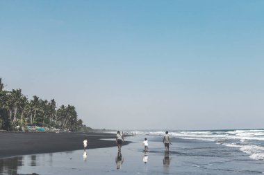 Bali, Endonezya - 19 Mayıs 2018: İki baba ve 2 oğlu siyah kum plaj.