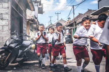 BALI, INDONESIA - MAY 23, 2018: Group of balinese schoolboys in a school uniform on the street in the village. clipart