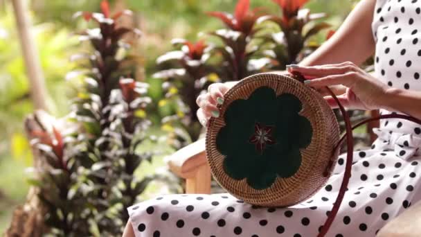 Close-up van stijlvolle rattand handtas in de tropische tuin. — Stockvideo