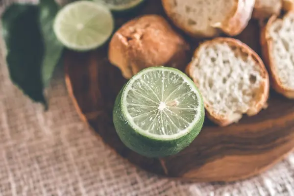 新鮮な緑のライムの木製テーブルの上のパンをスライス. — ストック写真