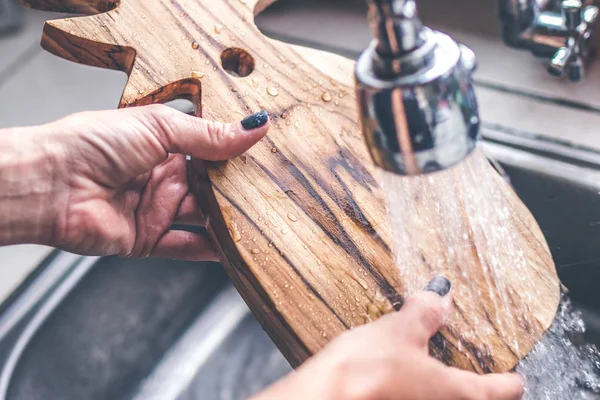 Teak ahşap kesme kurulu çamaşır. Tik kesme tahtası yıkama eller kadın.