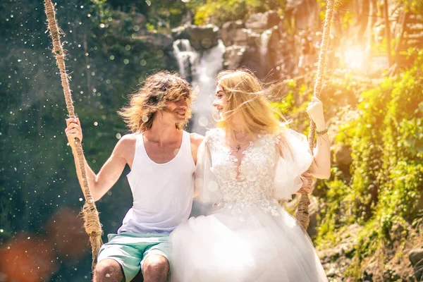 Young honeymoon couple swings in the jungle near the lake, Bali island, Indonesia. — Stock Photo, Image