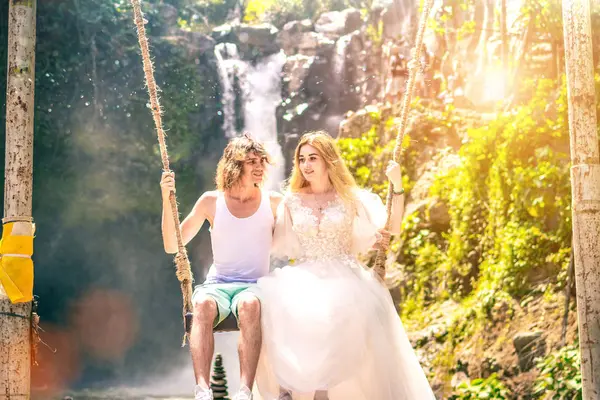 Young honeymoon couple swings in the jungle near the lake, Bali island, Indonesia. — Stock Photo, Image