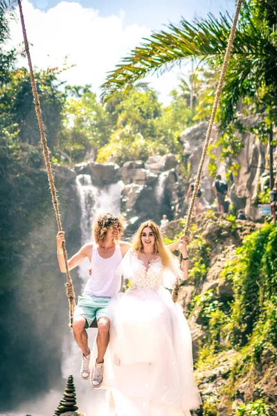 Young honeymoon couple swings in the jungle near the lake, Bali island, Indonesia. — Stock Photo, Image