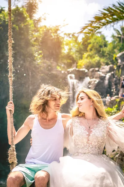 Young honeymoon couple swings in the jungle near the lake, Bali island, Indonesia. — Stock Photo, Image