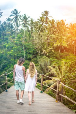 Genç balayı köprüde derin poz çift ormanda. Yağmur ormanları Bali Adası. Romantik ateş. Endonezya.