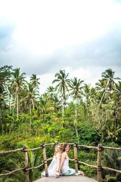 Young honeymoon couple posing on the bridge deep in the jungle. Rainforest of Bali island. Romantic shoot. Indonesia. — Stock Photo, Image