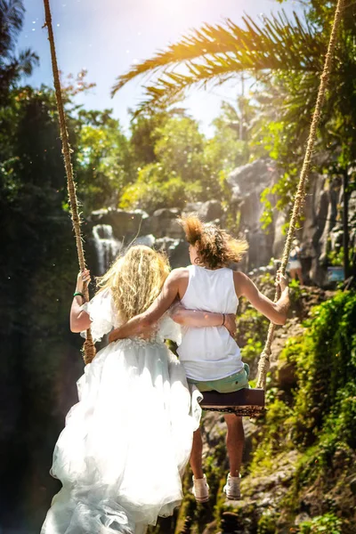 Young honeymoon couple swings in the jungle near the lake, Bali island, Indonesia. — Stock Photo, Image