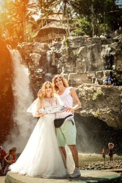 Lovely wedding couple against waterfall on sunset, tropical island of Bali. — Stock Photo, Image