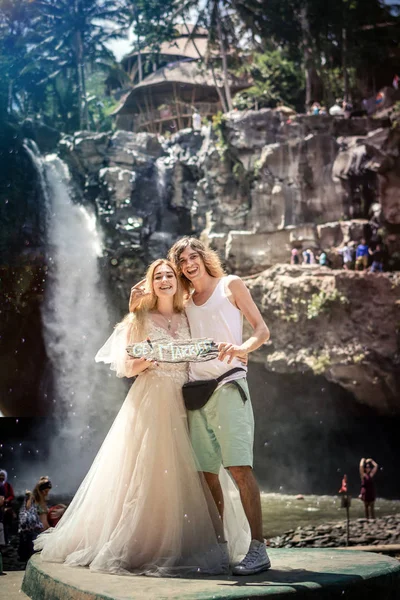 Lovely wedding couple against waterfall on sunset, tropical island of Bali. — Stock Photo, Image