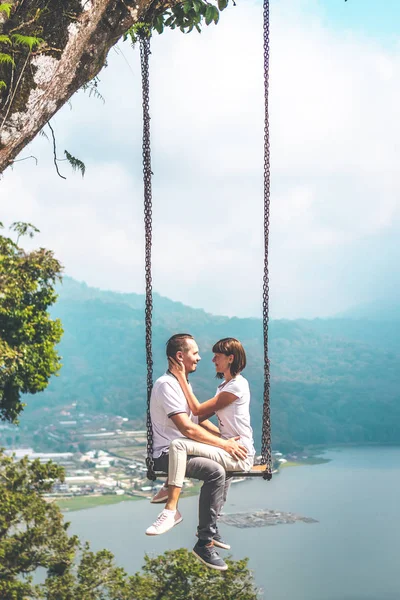 Young honeymoon couple swings in the jungle near the lake, Bali island, Indonesia. — Stock Photo, Image