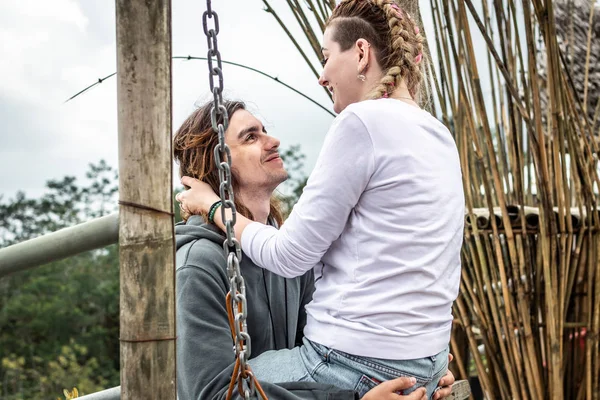 Young honeymoon couple swings in the jungle near the lake, Bali island, Indonesia.