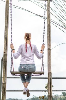 Güzel genç bir kadın yaz günü açık havada salıncakta.