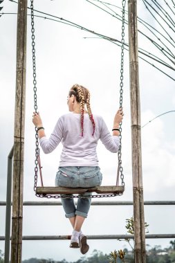 Güzel genç bir kadın yaz günü açık havada salıncakta.