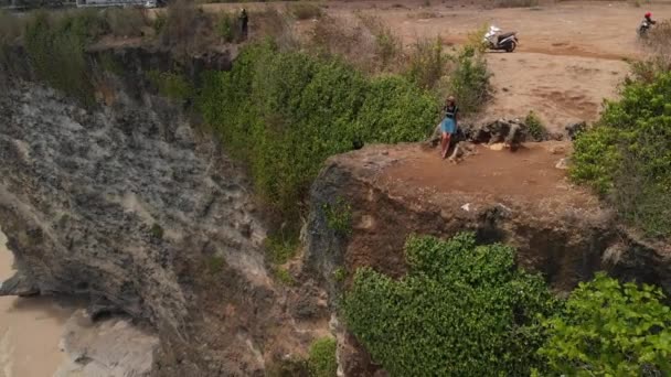 Mutlu sağlıklı romantik kadını uçurum üzerinde oturan 4 k hava dron görüntüleri. Güzel seyahat hareket kavramı. Bali Adası. — Stok video