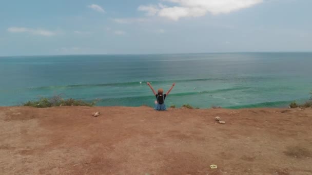 Imagens de drones aéreos 4K de uma mulher romântica e saudável sentada no penhasco. Belo conceito de movimento de viagem. Ilha de Bali . — Vídeo de Stock