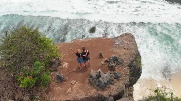 Imágenes aéreas de aviones no tripulados 4K de parejas en el acantilado. Increíble concepto de viaje. Isla de Bali . — Vídeo de stock