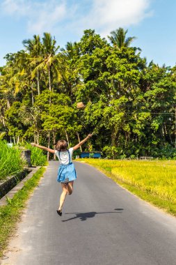 Tropikal Hindistan cevizi avuç içi ve tropik ağaçları ile bir yolda hasır şapka olan mutlu kadın portresi. Bali Adası.