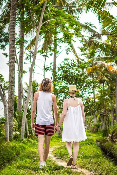 Young honeymoon couple walking among rice fields. Beautiful trip of newleds to Bali island, Indonesia. Nature, summer, green, bright. — Stock Photo, Image